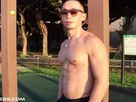 Young and fit Asian man shows off his muscles outdoors.